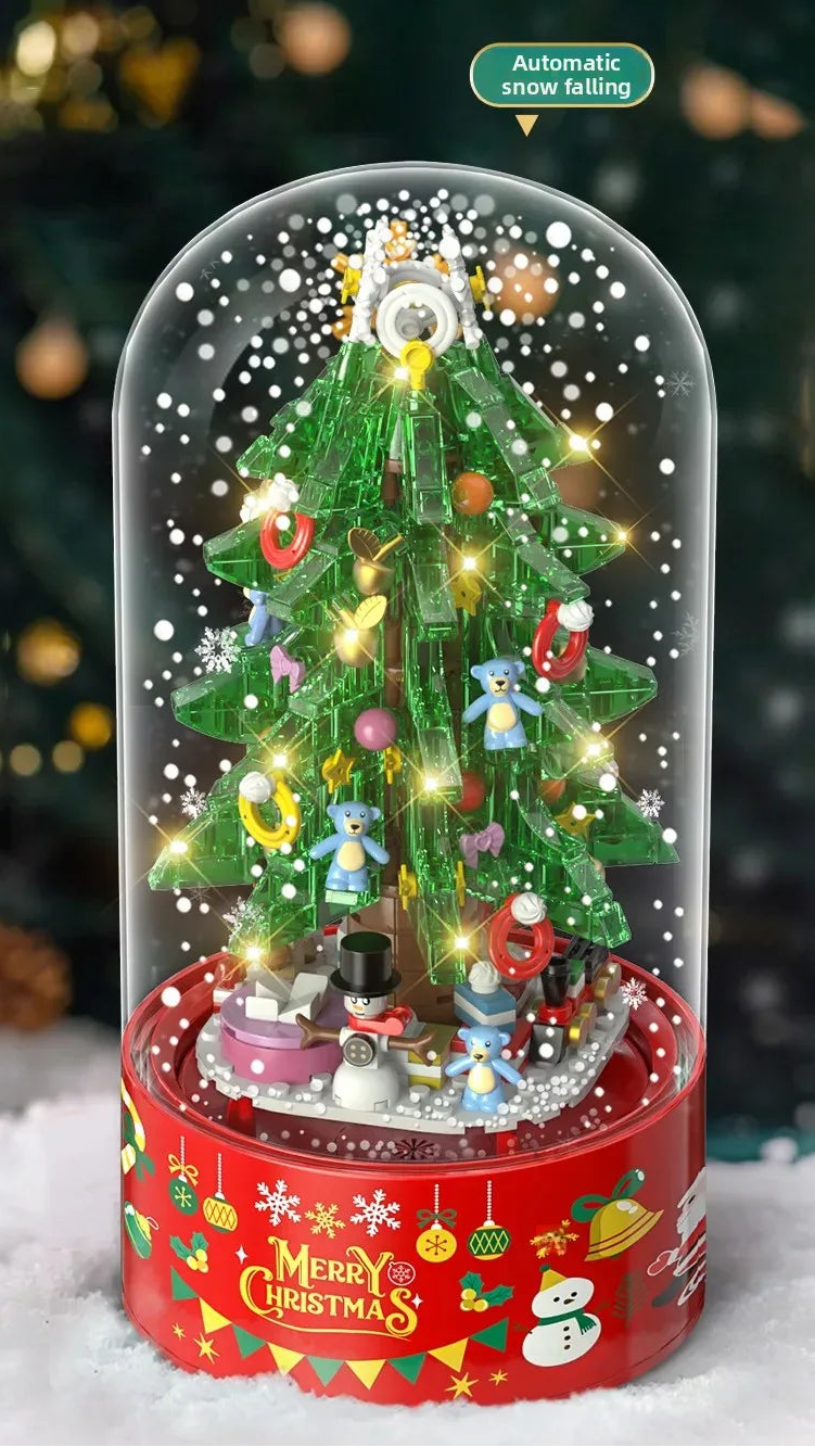 Decorative Christmas tree in a glass dome with animated snow and lights, on a snowy surface.